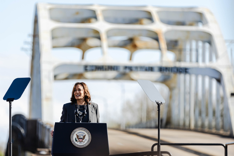A woman standing in front of a bridge.