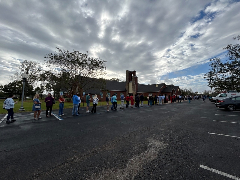A line of people outside a church under cloudy skies