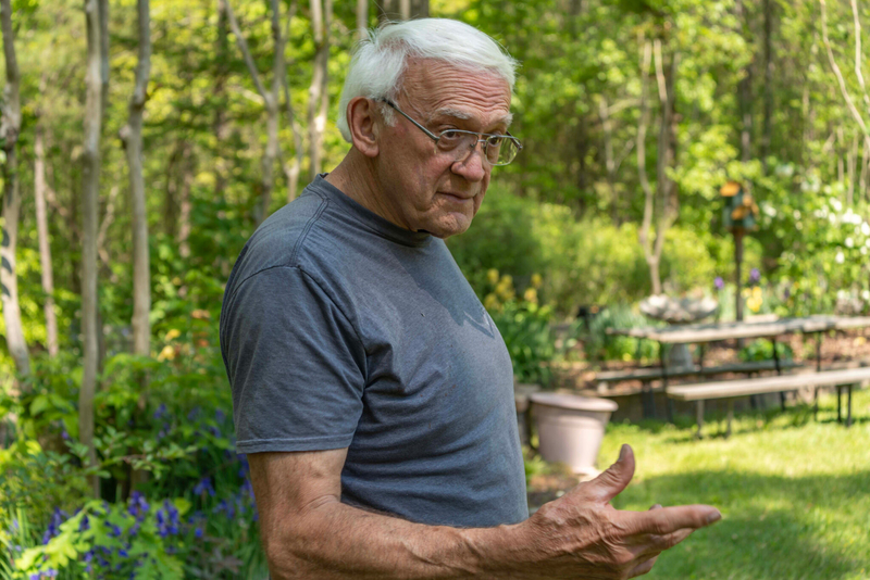 A man standing in a backyard in a gray T-shirt
