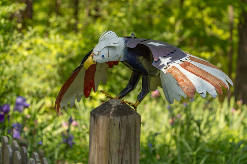 A painted sculpture of a bald eagle perched on a post