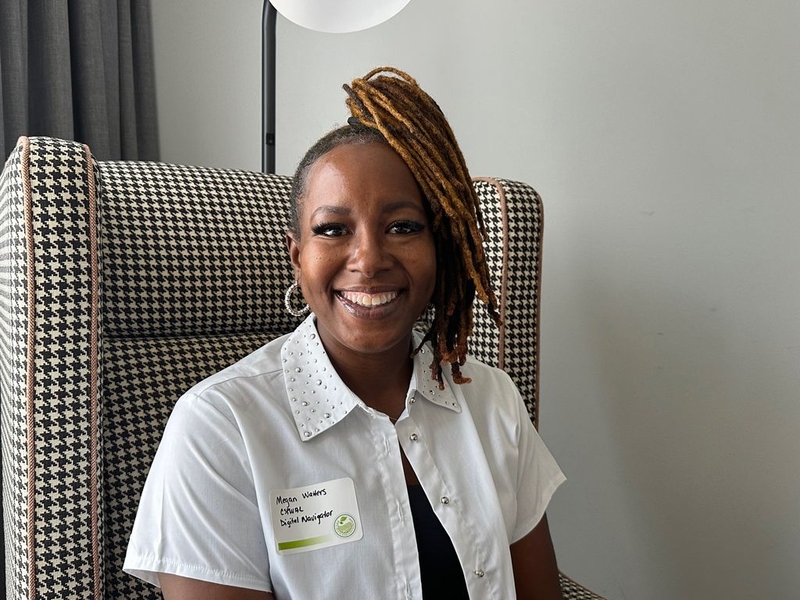 A woman seated in an upholstered chair and smiling toward the camera