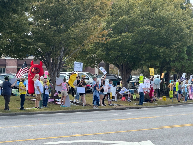 People lined up on a road holding signs