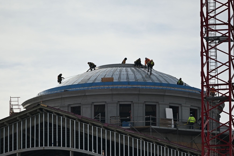 A group of workers walking across the rotunda of a large building, under construction