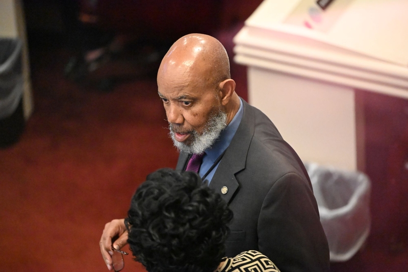 A man in a dark suit, blue shirt and purple tie