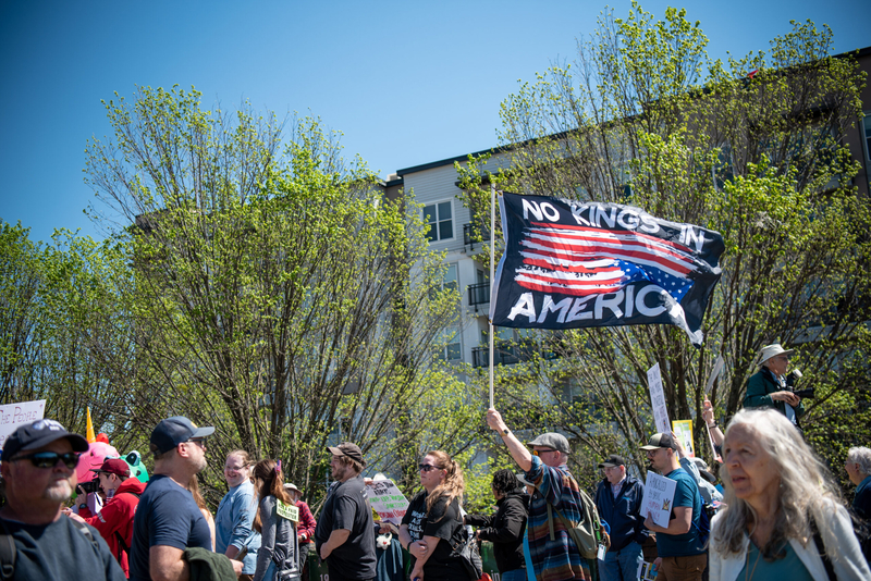 A person holding a flag saying No Kings in America