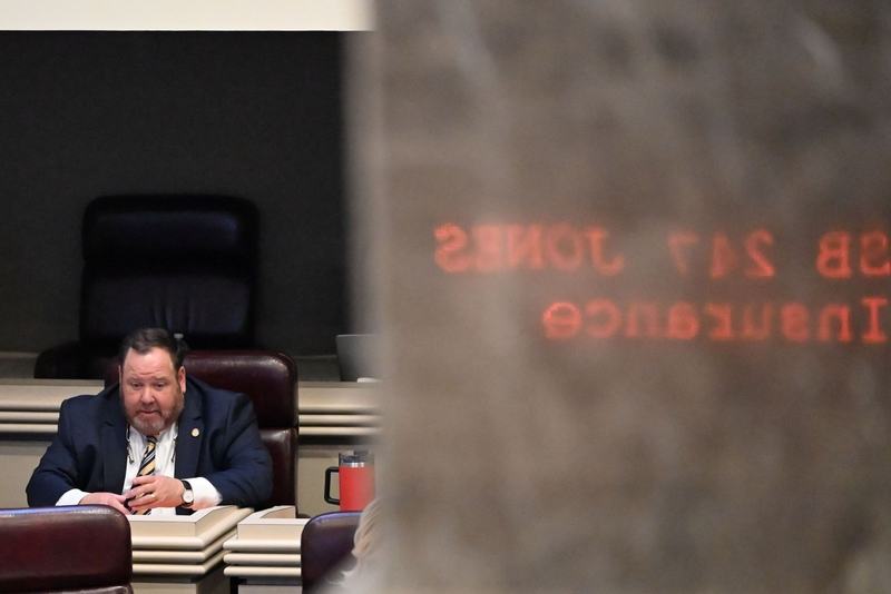 A man seated at a desk with text reflected on a pillar