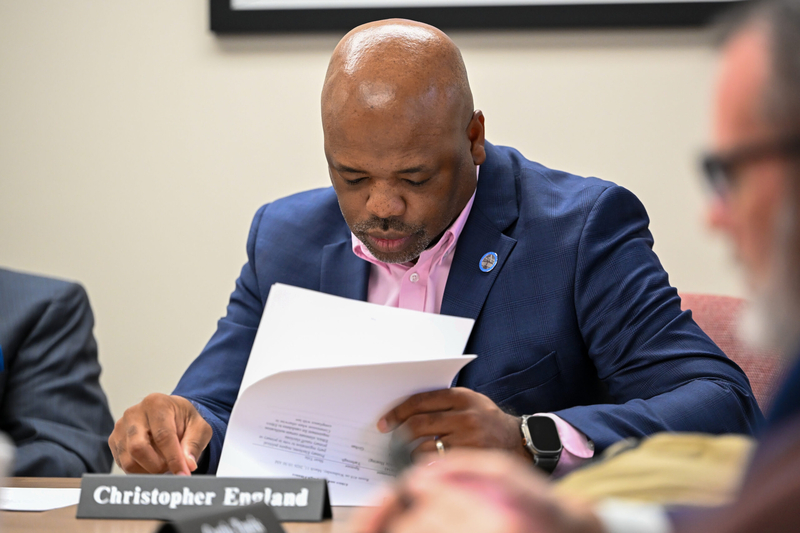 A man in a blue suit reading a piece of paper.