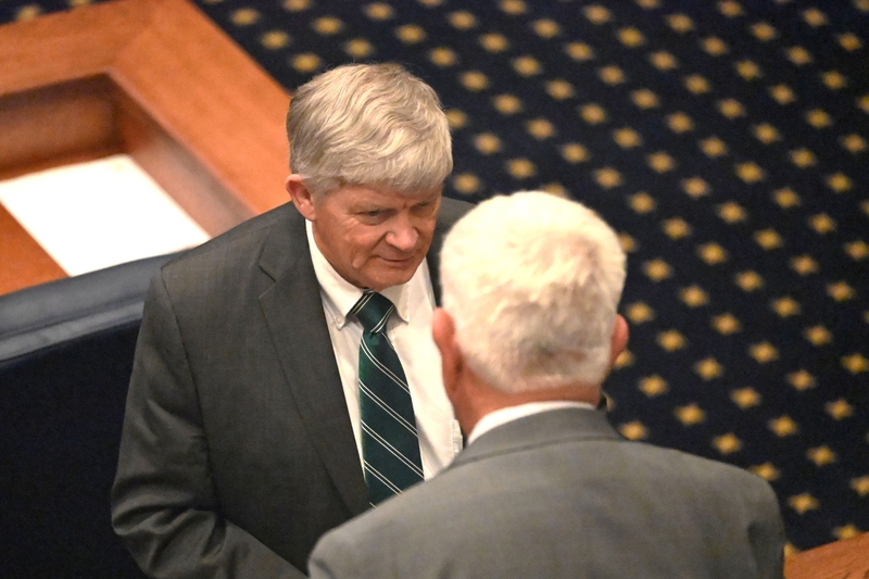 A man in a gray suit with a green and blue striped tie