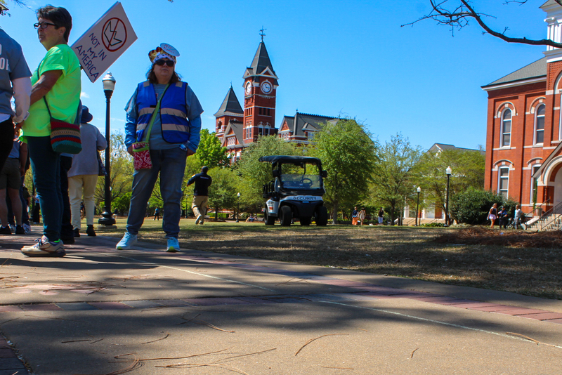 A golf cart parked on a lawn in the background with a sidewalk with a chalk line drawn in the foreground.