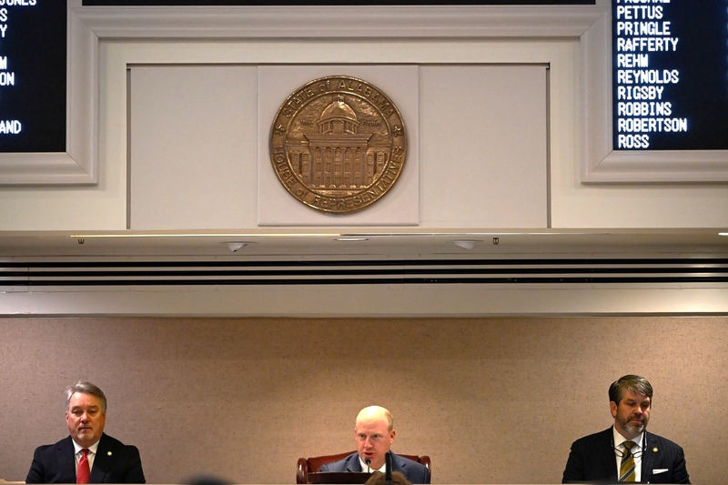 Three men seated on a dais