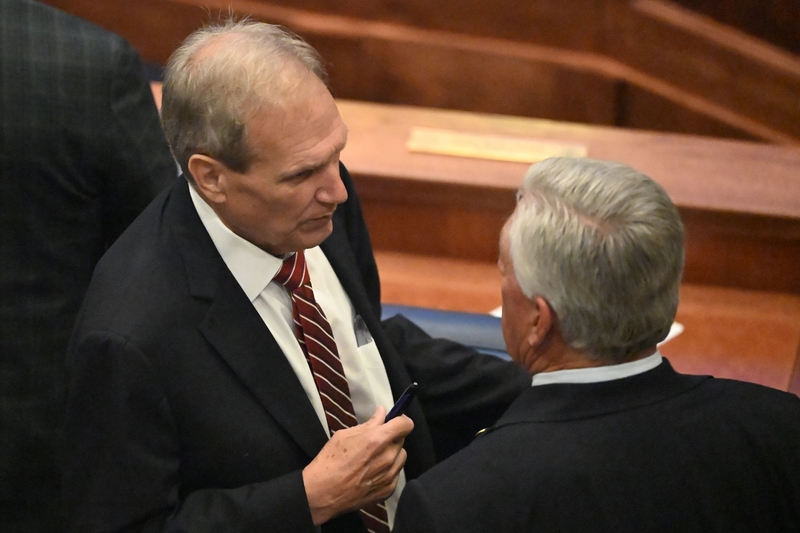 A man in a red and white striped tie speaking