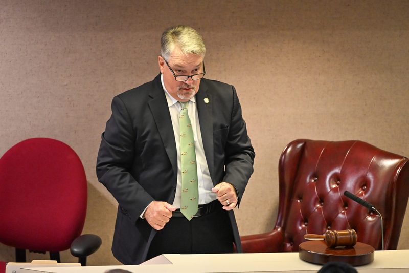 A man in a suit standing behind a desk.