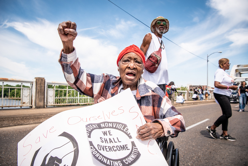 A woman holding a sign saying Save OUrselves