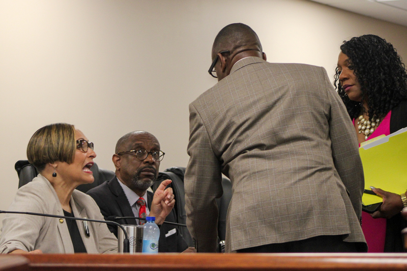 A group of men and women huddled around a desk discussing legislation.