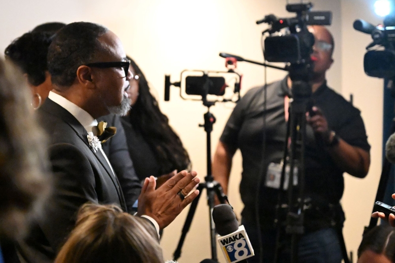 A man in a bowtie speaking to reporters