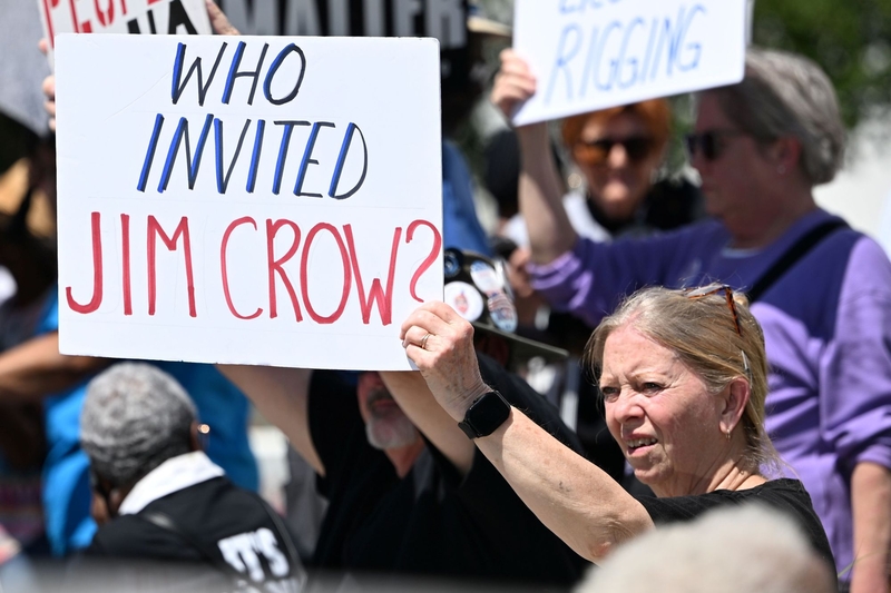 A woman holding a sign saying Who invited Jim Crow