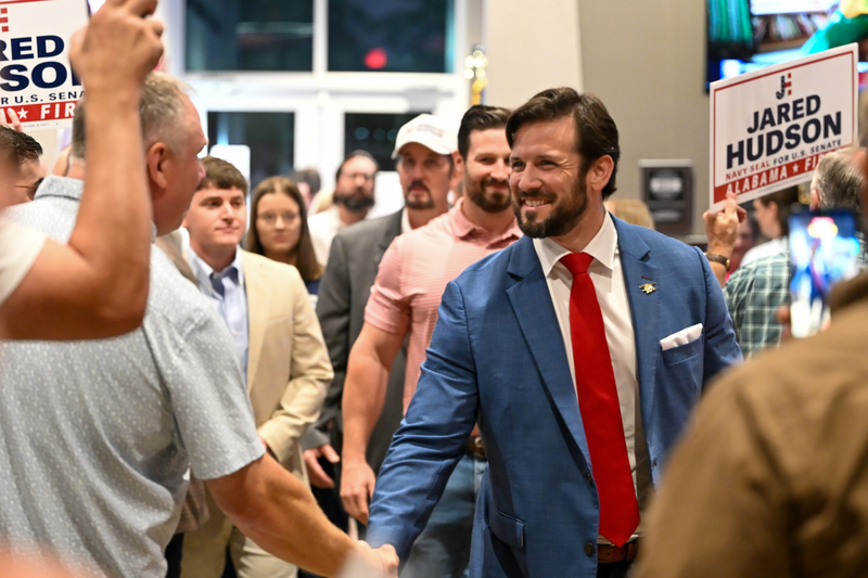 A man in a blue suit shaking another man's hand.