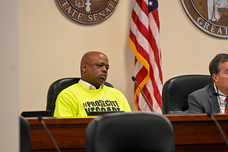A man in a yellow shirt sitting at a desk.