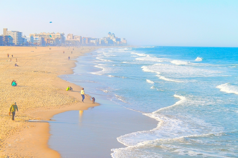 People walk along the beach in Ocean City, Maryland, with the city skyline seen in the distance in spring of 2024.