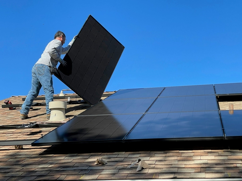A man installs solar panels to a residential roof.