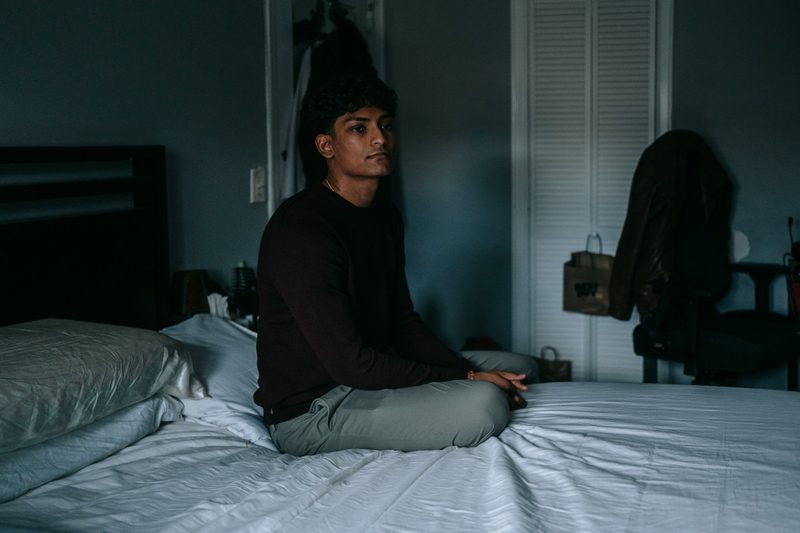 Brandon Bishunauth sits for a portrait inside his family's home.