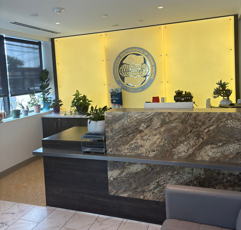 A polished-looking waiting area with plants, a couch, and a desk next to a window. The IBOTU logo is on the wall behind the desk.
