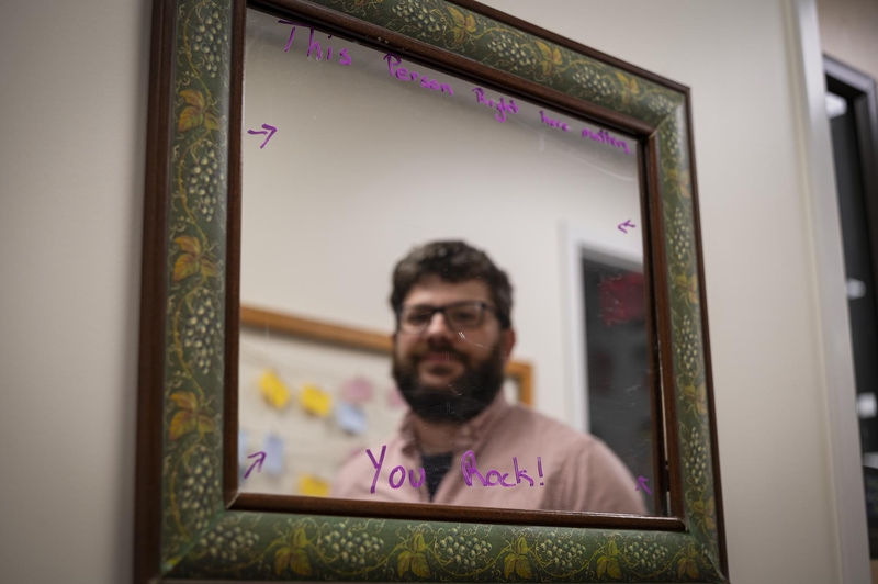 A man with a beard in front of a mirror.