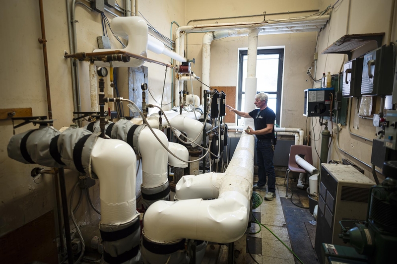 A man standing in a room with pipes and pipes.