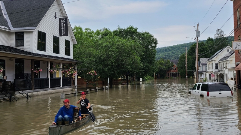 two people in a canoe on a flooded street.