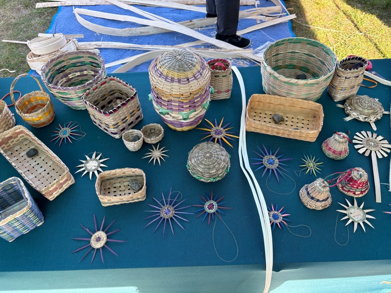 A variety of woven baskets, small containers, and star-shaped ornaments displayed on a dark table.