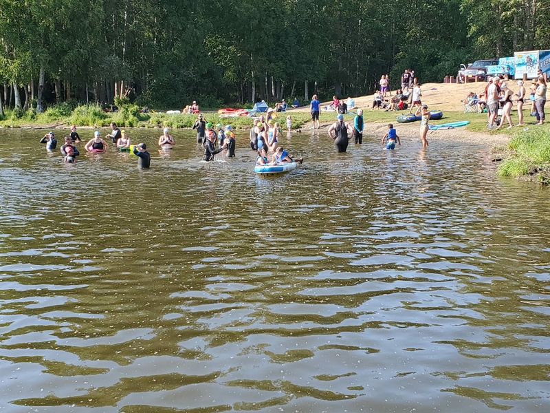 Competitive swimmers prepare for a race in Anchorage's Little Campbell Lake on June 22, 2022. The lake, within Kincaid Park, is a popular summer gathering site for swimmers, boaters, sunbathers and fishers. It is one of the sites in Alaska's largest city containing PFAS contaminants, according to a study by the nonprofit Alaska Community Action on Toxics. (Photo by Yereth Rosen/Alaska Beacon)