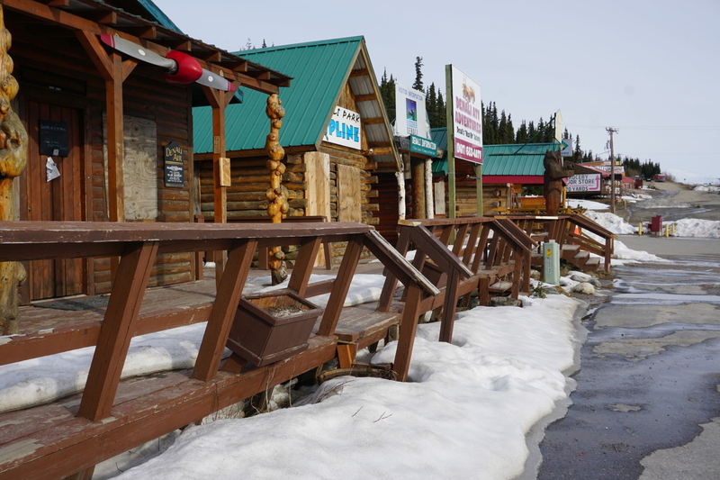 Tourist businesses lining the Parks Highway outside of the Denali National Park entrance, at a strip nicknamed "Glitter Gulch," are seen on May 5. The shops, restaurants and tour companies, not yet open that day, depend on Denali crowds. Last year, with the second half of the road closed, there were more opportunities for some companies but challenges for others, like restaurants, which did not have the staffing to manage crowds. (Photo by Yereth Rosen/Alaska Beacon)