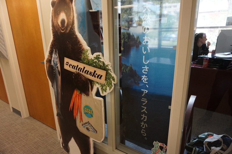 Hannah Scholosstein, international marketing and grants manager for the Alaska Seafood Marketing Institute, works in her office in Juneau on May 22, 2025, amid promotional materials. (Photo by Yereth Rosen/Alaska Beacon)