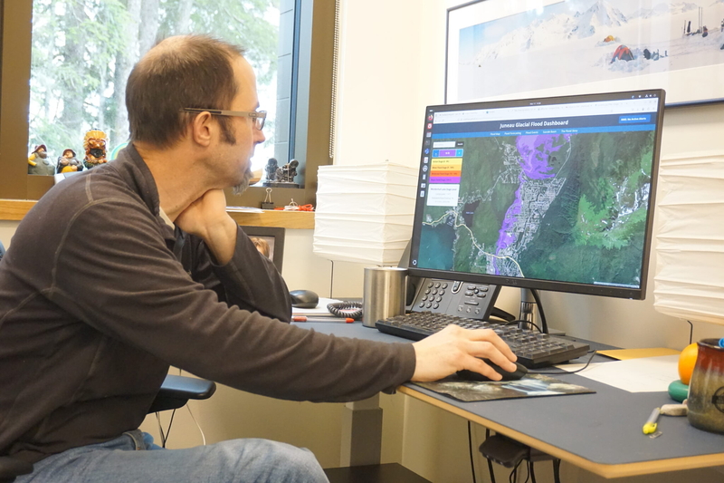 Jason Amundson, a professor of geophysics at the University of Alaska Southeast, pulls up the Juneau Glacial Flood Dashboard at his office on March 11, 2025. The dashboard, still in development at the time, shows how far floods waters would reach into neighborhoods, depending on different scenarios. The dashboard went online in May. (Photo by Yereth Rosen/Alaska Beacon)