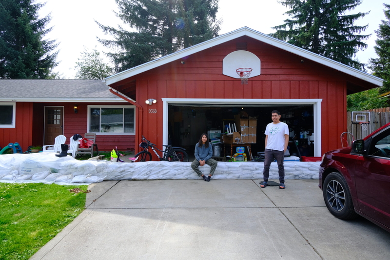 Israel Katzeek, with nephew Raiden Johnson-Katzeek, outside their home in the Mendenhall Valley, where they prepared a flood barrier but only saw minimal flooding of the street from the glacial outburst event on August 13, 2025 (Photo by Corinne Smith/Alaska Beacon)