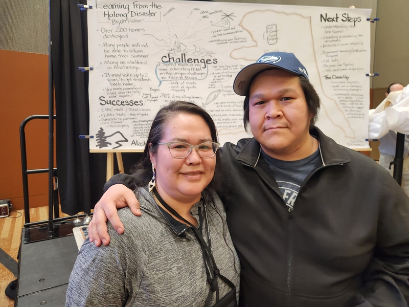 Lucy Martin and Dustin Evon of Kwigillingok stand near the stage on Feb. 2, 2026, at the Alaska Forum on the Environment, held in Anchorage They two were part of a presentation , on ex-Typhoon Halong. Behind them are notes taken during the presentation. (Photo by Yereth Rosen/Alaska Beacon)