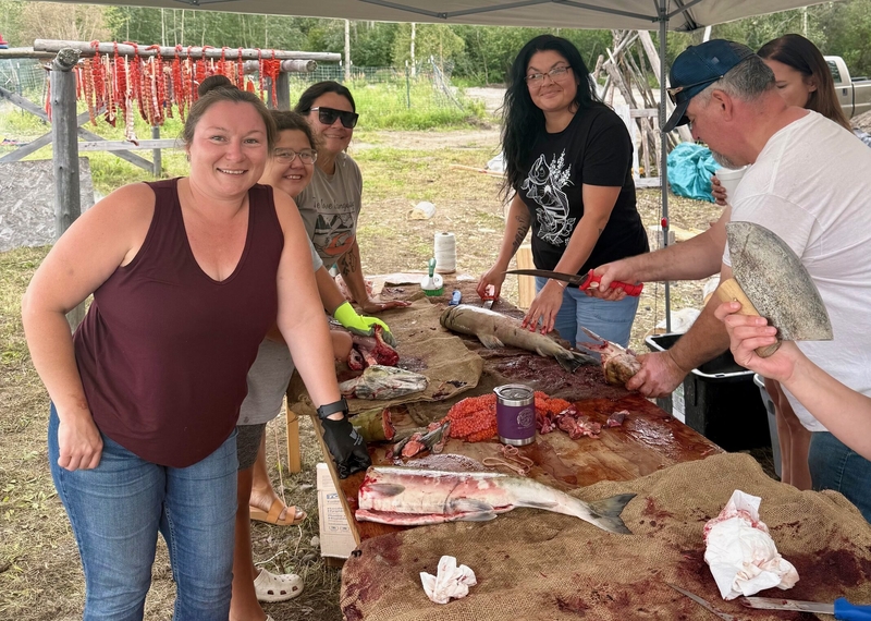 Eva Burk, Jessica and Rory Black, Ariella Bradley, Fatima Lord-Minano and Charlie Wright cut salmon during an August 2025 cultural camp held in Nenana. The youth and adults in the camp were able to harvest and process a few chum salmon in 2025, for the first time in several years. Burk, who is from Nenana, is a tribal representative on the North Pacific Fishery Management Council's advisory panel. Wright is secretary and treasurer of the Tanana Chiefs Council. Both have argued for tighter restrictions on at