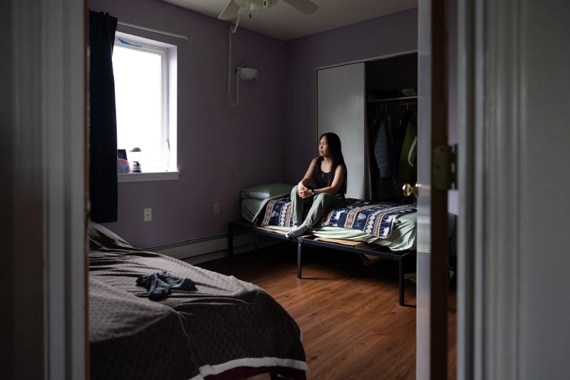 Ariel Friend, 20, sits on her bed in a room she shares with her aunt in Bethel, Alaska, on June 28, 2026. Friend relocated from Kwigillingok after ex-Typhoon Halong struck the village. (Katie Basile for Anchorage Press)