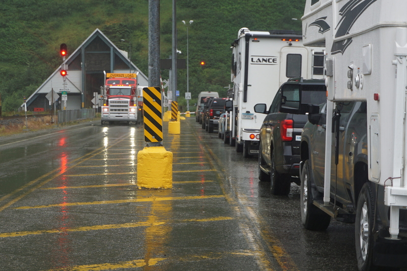 A truck emerges from the Anton Anderson Memorial Tunnel on the Whittier side on July 16, 2025, as vehicles are lined up in lanes on the right in preparation to leave Whittier through the tunnel. The tunnel has only one lane, and traffic goes through in shifts. It also accomodates train traffic. The tunnel was built by the Army during World War II as a rail link enabling Whittier to serve as a supply and support center. It was later converted, and began accomodating auto traffice as well as trains in 2000. I