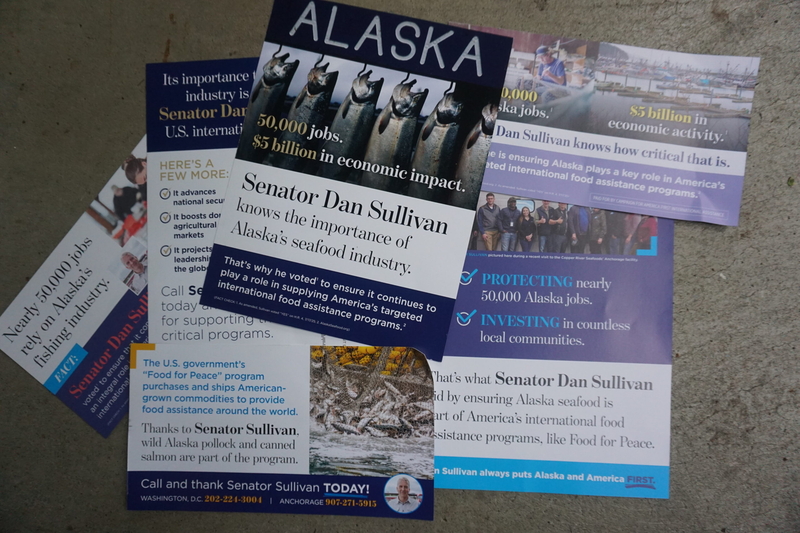 Fish-themed mailers urging support for incumbent Sen. Dan Sullivan, R-Alaska, are seen on Sept. 18, 2026. (Photo by Yereth Rosen/Alaska Beacon)