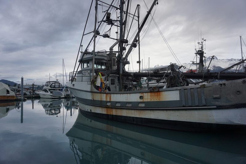A fishing vessel is docked in Seward is reflected in the water on June 26, 2026. (Photo by Yeeth Rosen/Alaska Beacon)