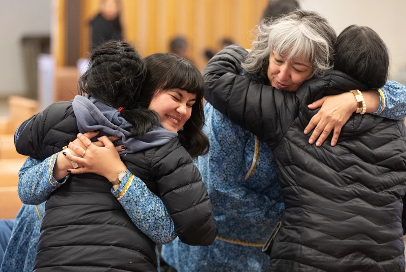 Community members at the Shishmaref Lutheran Church in Alaska embrace Nyché Andrew, left, and her mother, Jacqueline Agugaq Walluk, after a memorial service for Tummassak, an Alaska Native student who died more than 100 years ago while attending the Carlisle Indian Industrial School. (Credit: Charles Fox/Special to ICT)