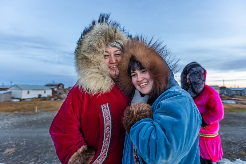 Nyché Andrew, center, and her mother, Jacqueline Agugaq Walluk, brave the cold and wind for an evening walk along the coast at Shishmaref, Alaska, on Oct. 3, 2026. Friend Madeline Gupta is at right. (Credit: Charles Fox/Special to ICT)
