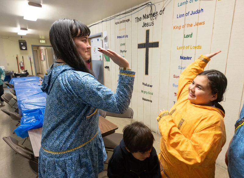 Nyché Andrew, left, high-fives Hayden (Saataq) Eningowuk during a community meal following the reburial of Tummassak at the Lutheran cemetery in Shishmaref, Alaska, on Oct. 4, 2026. Tummassak died more than 100 years ago while attending the Carlisle Indian Industrial School and was finally returned home. Schoolchildren were among those who attended her memorial service. (Credit: Charles Fox/Special to ICT)