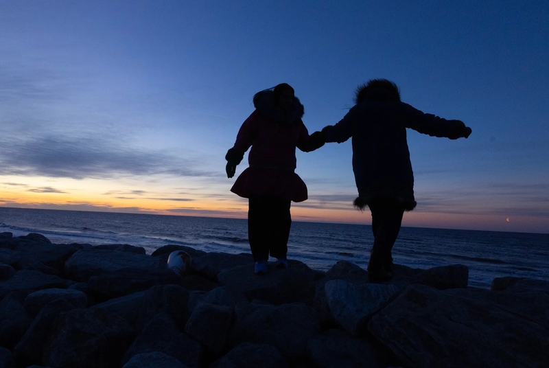 Nyché Andrew, left, and her mother, Jacqueline Agugaq Walluk, walk along the water at Shishmaref, Alaska, on Oct. 3, 2026.