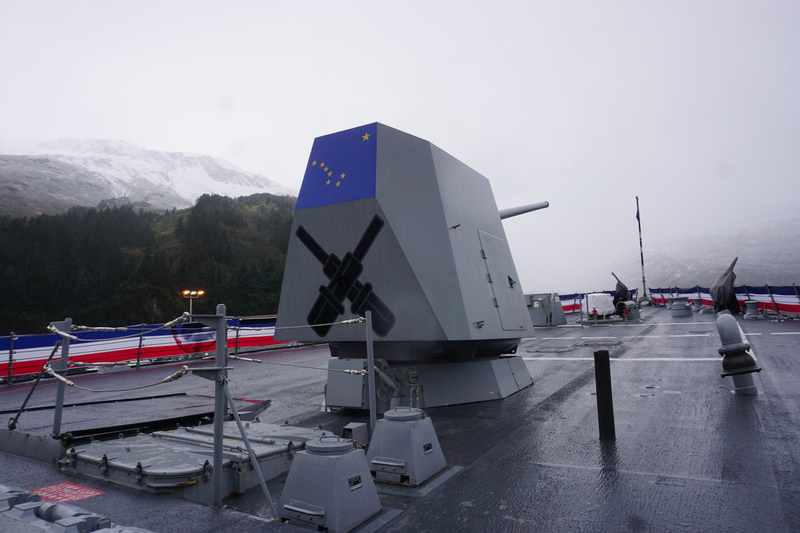 The battery gun on the deck of the USS Ted Stevens, seen Oct. 1, 2026, in the Prince WIlliam Sound town of Whittier, is decorated with an Alaska flag. The new Navy destroyer pis named for the late U.S. Sen. Ted Stevens, a Navy veteran. (Photo by Yereth Rosen/Alaska Beacon)
