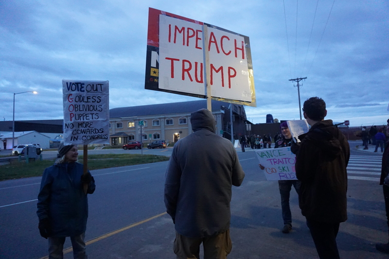 Protestors hold signs outside of the Fairbanks hangar where Vice President JD Vance delivered a speech at a campaign rally for U.S. Sen. Dan Sullivan, R-Alaska. (Photo by Yereth Rosen/Alaska Beacon)