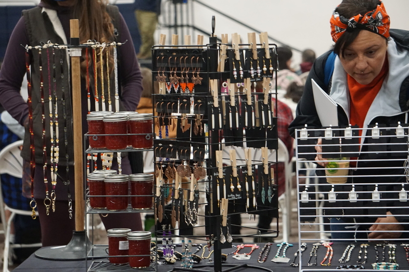A shopper examines handmade jewelry on display at the Oct. 12, 2026, Indigenous Peoples Day celebration at Alaska Pacific University. (Photo by Yereth Rosen/Alaska Beacon)