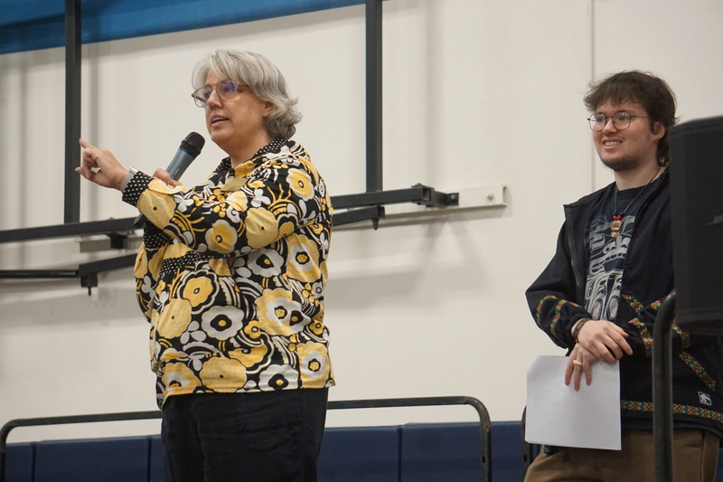 Alaska Pacific University President Janelle Vanasse speaks to the audience at the start of the school's Indigenous Peoples Day event on Oct. 12, 2026. With her on the state is Oliver Iqitainguq Tyrrell, a Yup’ik and Iñupiaq social work student at the Unviersity of Aalska Anchorage, who served as the event's emcee. (Photo by Yereth Rosen/Alaska Beacon)