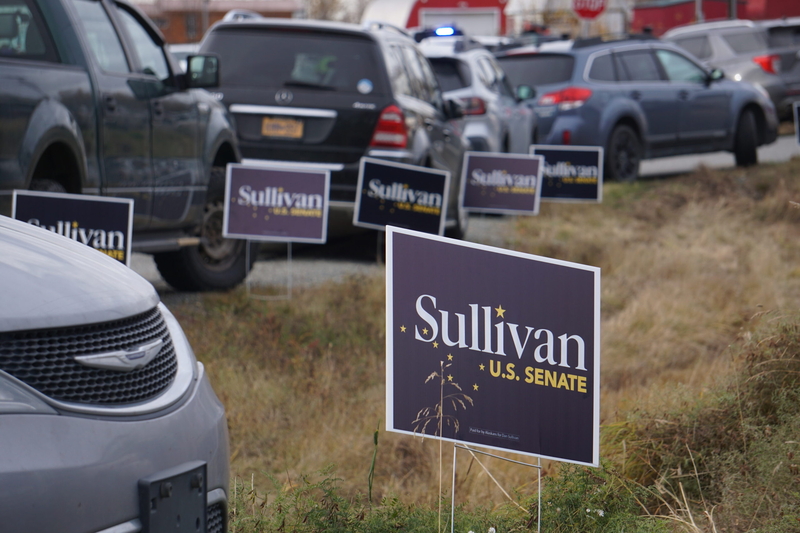 Campaign signs for U.S. Sen Dan Sullivan, R-Alaska, line a packed parking area near the Church on the Rock in Wasilla on Oct. 13, 2026. The church was used as a bus shuttle site for people attending a campaign rally headlined by President Donald Trump. Trump was in town to stump for Sullivan. The rally was held at the Curtis D. Menard Sports Center. (Photo by Yereth Rosen/Alaska Beacon)